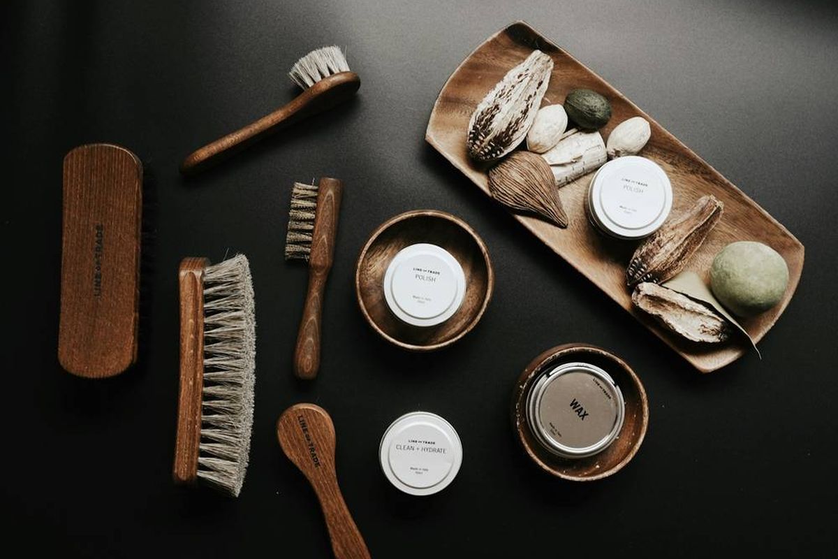 Polished leather shoes with a brush, cloth and shoe polish on a wooden surface