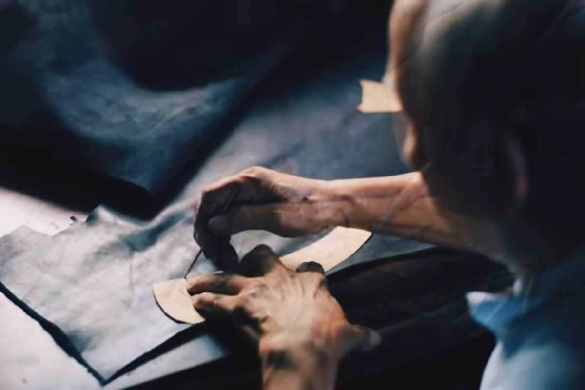 Shoemaker crafting leather shoes on lasts in a footwear manufacturing workshop