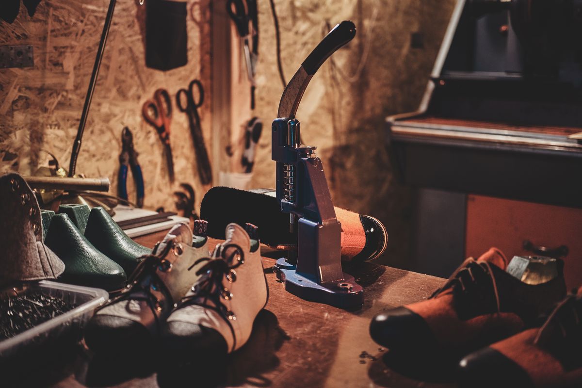 Craftsman replacing the sole of a worn leather shoe at the Nylex Shoes repair workbench in Port Louis
